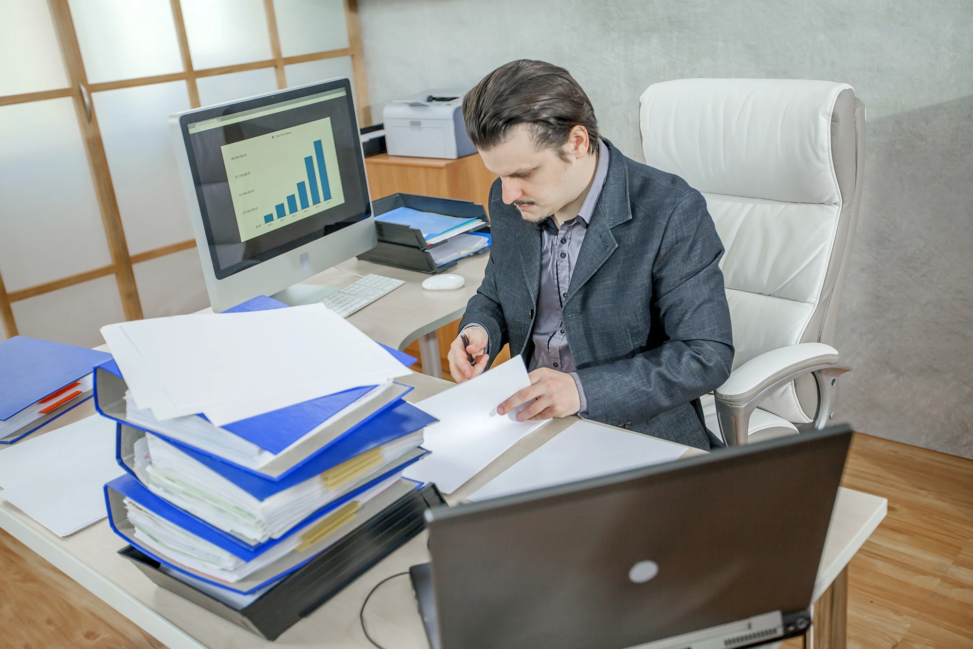 Professional preparing financial statements with documents, and a laptop on the desk.